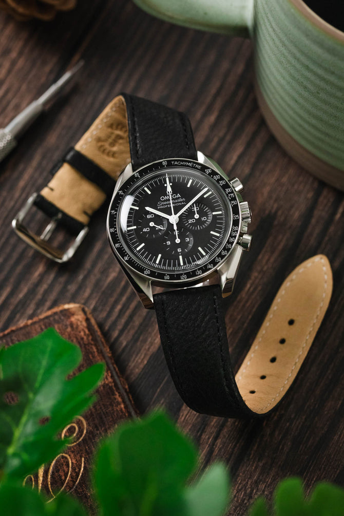 Image showing the flexibility of RIOS 1931 Watch strap fitted to a Speedy with a moody wooden background, coffee cup and leafs