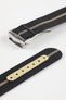 Angled close-up of a black ribbed nylon watch strap with a central cream stripe, featuring a brushed silver deployant clasp with an engraved logo. A separate strap section shows a cream-colored reinforced panel with evenly spaced adjustment holes, all set against a clean light grey background.
