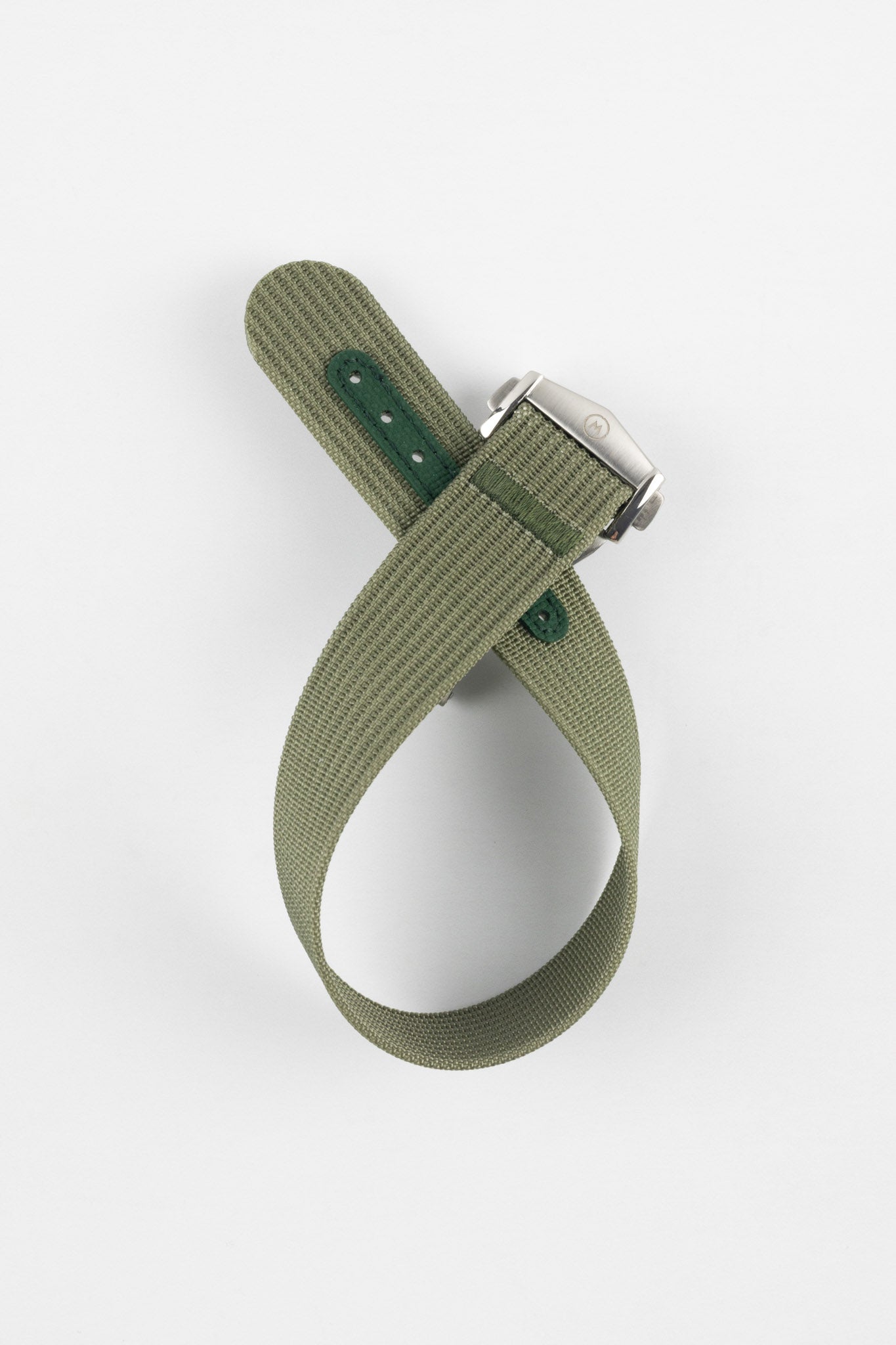 A top-down shot of a green ribbed-nylon watch strap coiled into a loop against a white background, featuring a brushed stainless steel buckle with a circular logo.