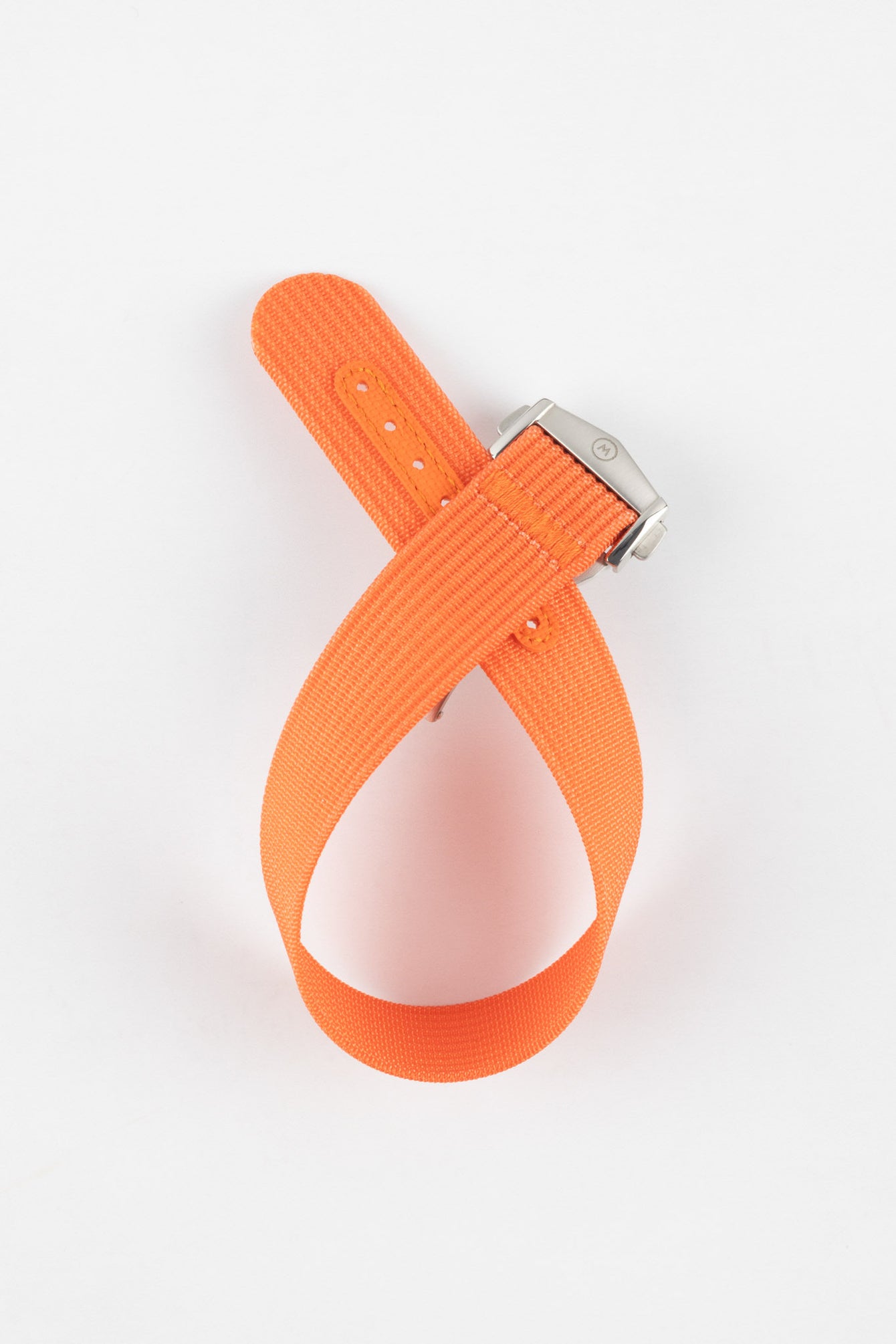 Bright orange ribbed nylon watch strap displayed looped on a light grey background, featuring a textured woven surface and a brushed silver deployant clasp with an engraved logo. The strap includes an orange reinforced section with evenly spaced adjustment holes, highlighting its bold color and durable construction.
