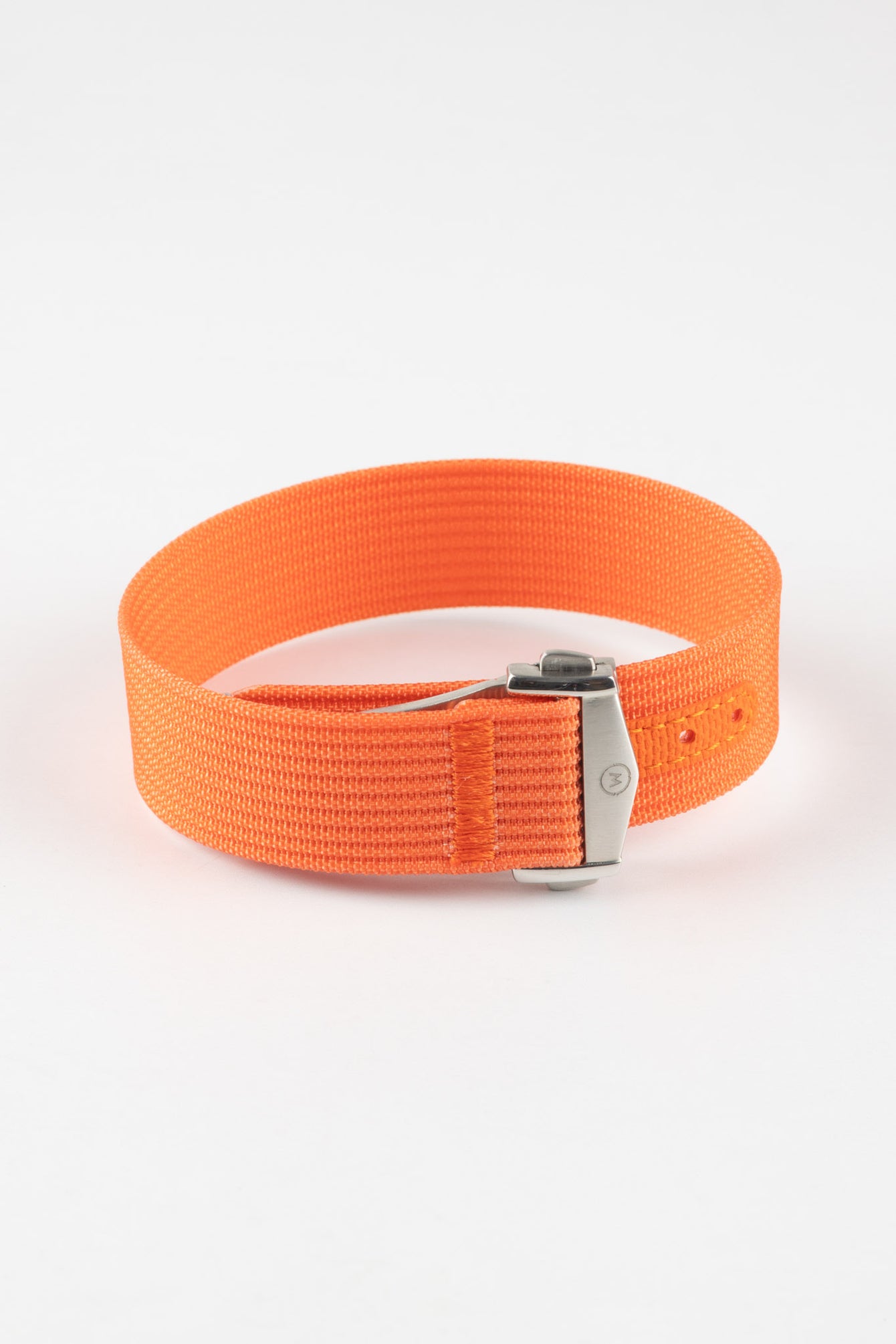 Close-up of a bright orange ribbed nylon watch strap arranged in a loop on a light grey background. The strap features a textured woven finish and a brushed silver deployant clasp with an engraved logo. An orange reinforced section with evenly spaced adjustment holes is visible near the clasp, highlighting the bold color and durable construction.