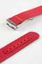 Angled close-up of a red ribbed nylon watch strap showing the textured woven surface and a brushed silver deployant clasp with an engraved logo. A separate strap section displays a matching red reinforced panel with neatly stitched edges and evenly spaced adjustment holes, all set against a clean light grey background.