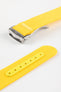 Angled close-up of a bright yellow ribbed nylon watch strap highlighting its textured woven surface and a brushed silver deployant clasp with an engraved logo. A separate strap section shows a matching yellow reinforced panel with clean stitching and evenly spaced adjustment holes, all set against a light grey background.
