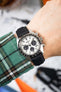 Close-up of a Seiko chronograph with a white dial on a black strap worn on a wrist.