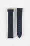 Two black textured watch strap pieces with blue contrast stitching displayed side by side on a light grey background; one strap is attached to a brushed silver deployant clasp with an engraved logo, while the other features a row of adjustment holes.