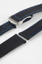 Angled close-up of a black textured watch strap with blue contrast stitching, featuring a brushed silver deployant clasp with an engraved logo, alongside separate strap sections, all displayed on a light grey background.