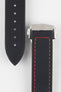 Close-up of a black textured watch strap with red contrast stitching, showing one section with evenly spaced adjustment holes and the other attached to a brushed silver deployant clasp with an engraved logo, set against a light grey background.