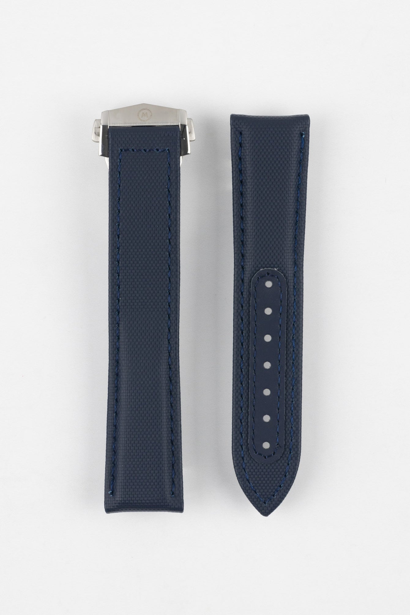 Two dark blue textured watch strap pieces displayed vertically on a light grey background, featuring subtle matching blue stitching; one strap is fitted with a brushed silver deployant clasp, while the other shows a row of adjustment holes down the center.