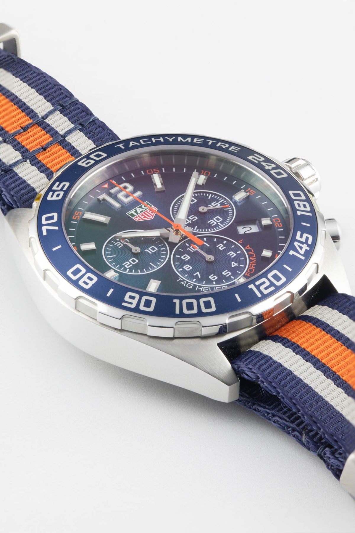 TAG Heuer Formula 1 Gulf Edition chronograph with a blue, white, and orange NATO strap shown in a close-up macro photograph on a white background.