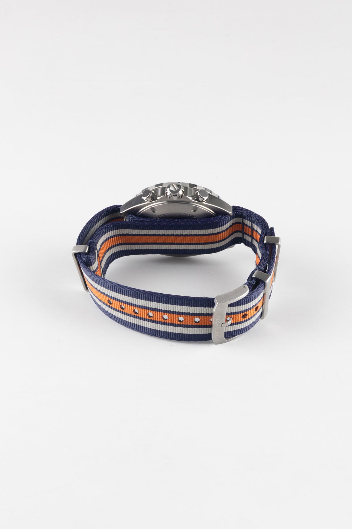 Premium TAG Heuer Formula 1 Gulf Edition chronograph watch featuring a stainless steel case, chronograph pushers, and a blue, white, and orange striped NATO-style fabric strap inspired by iconic Gulf racing colours. Detailed rear-angle product photograph showcasing the signed TAG Heuer buckle, durable woven strap construction, stainless steel hardware, exceptional comfort, and distinctive motorsport-inspired styling. Ideal for collectors, racing enthusiasts, and everyday wear.