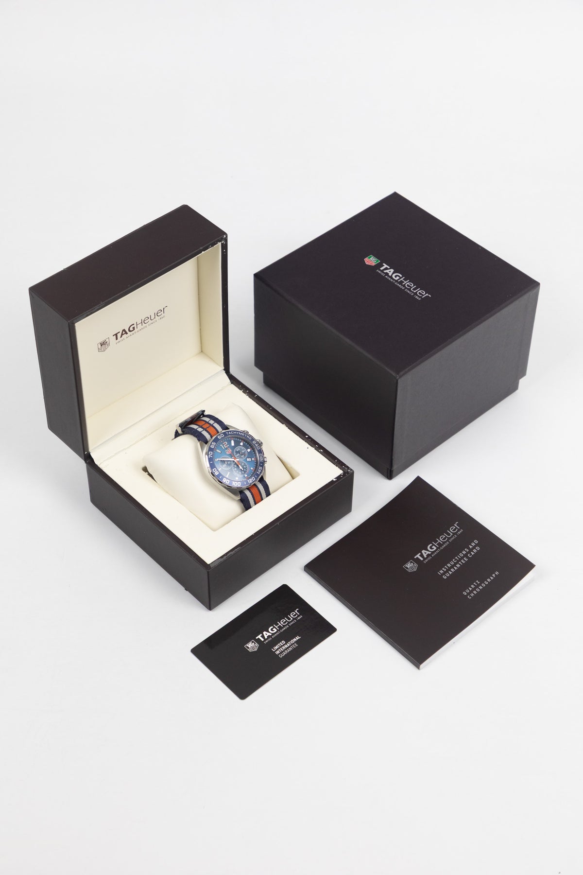 TAG Heuer Formula 1 Gulf Edition chronograph complete set with presentation box, manual, warranty card, and Gulf-striped NATO strap.