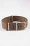 Close-up product shot of a brown ribbed nylon NATO‑style watch strap with brushed metal buckle and keepers, arranged in a loop on a plain light background, highlighting its woven texture and adjustment holes.