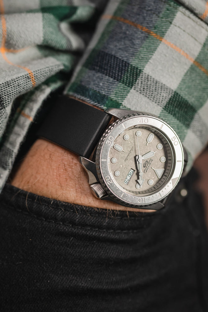 Seiko 5 Sports Cement SRPG61K1 and Black Bonetto Cinturini on wrist with hand in trouser pocket in sunlight