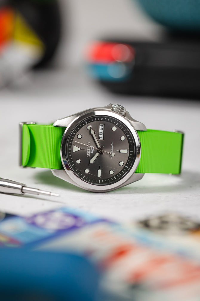 Seiko 5 Sports Anthracite Dial SRPE51K1 fitted with lime green bonetto centurini 328 rubber one piece strap curved and flat on table