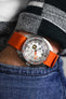 Doxa sub 300 searambler silver lung limited edition fitted with orange bonetto cinturini 328 premium rubber one piece watch strap on wrist with hand in pocket of enim trousers