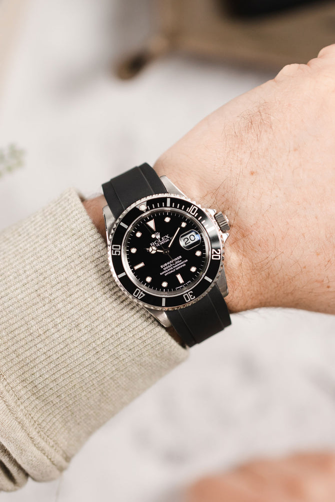 Rolex Submariner 16610 Oystersteel black dial and bezel fitted with crafter blue rx01 rubber watch strap in black on wrist with jumper
