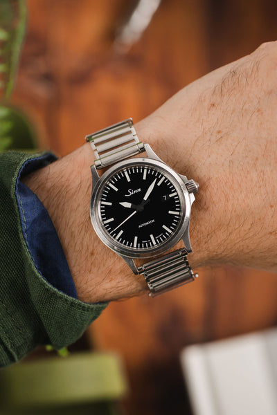 Sinn black dial fitted with Forstner Klip Stainless Steel Ladder-Style watch bracelet worn on wrist