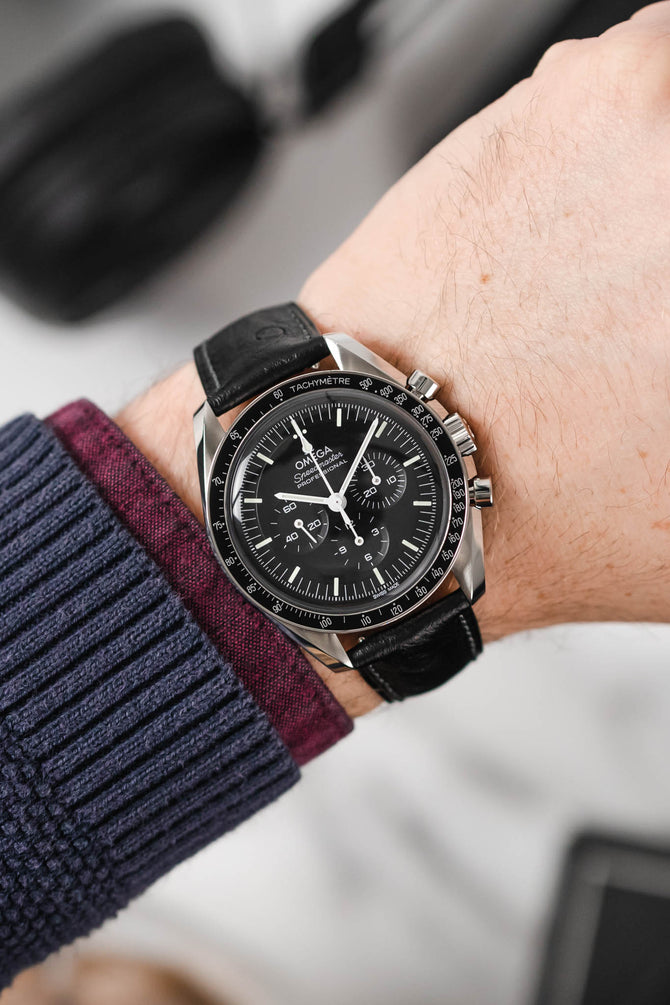 Black Omega Moonwatch Speedmaster fitted with Hirsch Massai Ostrich black leather watch strap worn on wrist