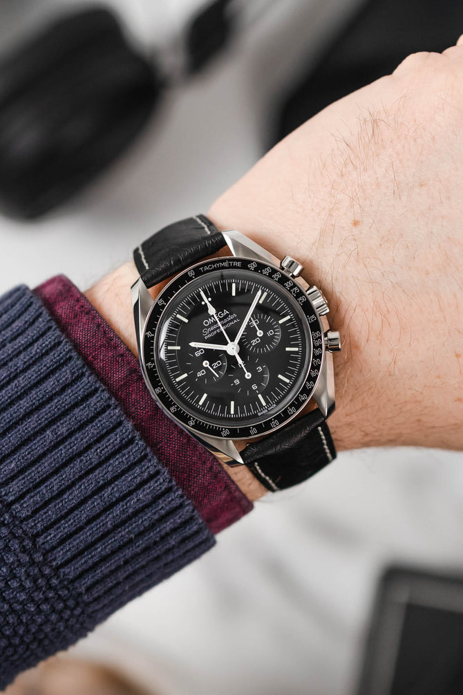 Black Omega Moonwatch speedmaster fitted with Hirsch Massai ostrich black leather and white stitch watch strap worn on wrist