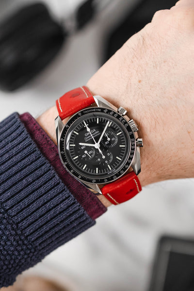 Black Omega Moonwatch Speedmaster fitted with Hirsch Massai Ostrich red with white leather watch strap worn on wrist