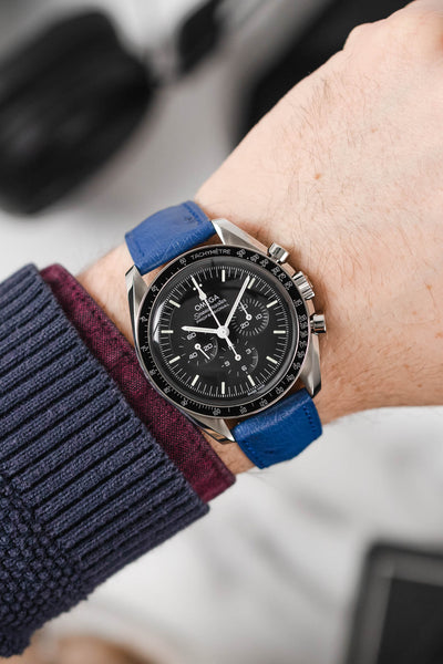 Black Omega Moonwatch Speedmaster fitted with Hirsch Massai Ostrich royal blue leather watch strap worn on wrist