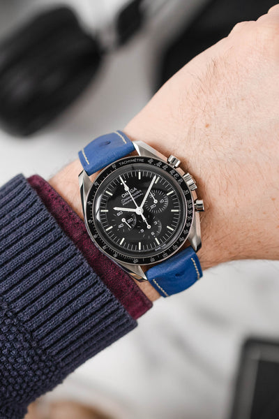 Black Omega Moonwatch Speedmaster fitted with Hirsch Massai Ostrich royal blue and white stitch leather watch strap worn on wrist